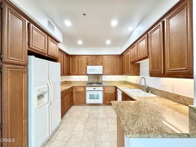 a large kitchen with stainless steel appliances granite countertop a refrigerator and a sink