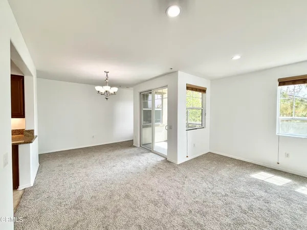 an empty room with chandelier fan and windows