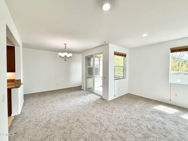 an empty room with chandelier fan and windows