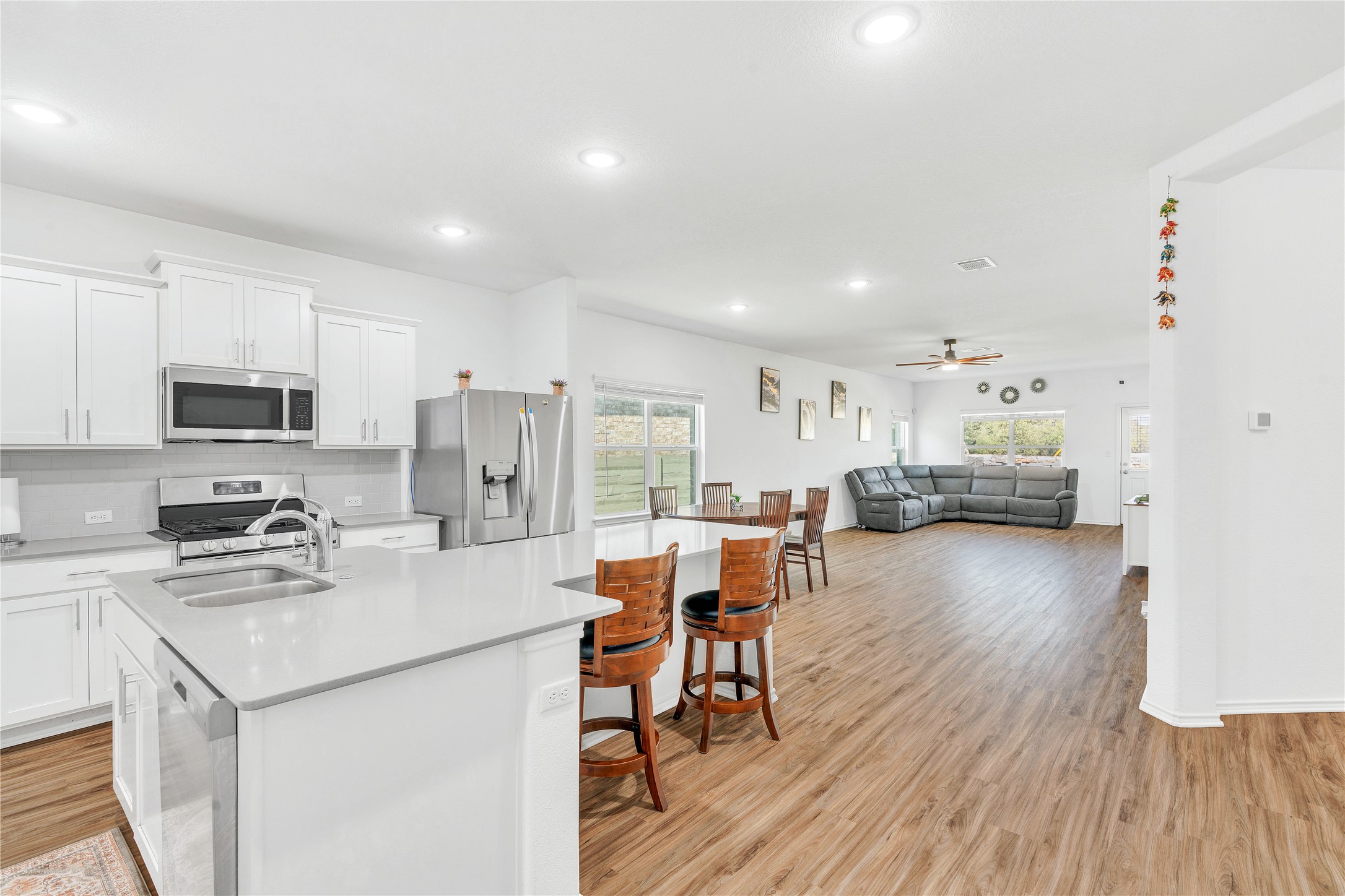 212 Saddle Mountain Road Georgetown, TX 78628 - Photo 3 of 38 a kitchen with stainless steel appliances a stove a refrigerator a sink dishwasher and a dining table with wooden floor