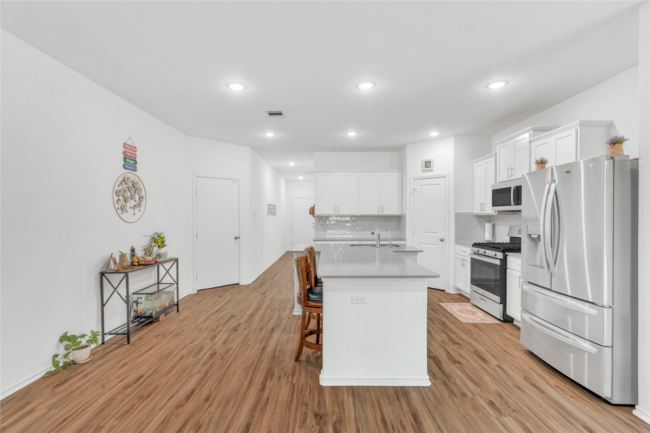 212 Saddle Mountain Road Georgetown, TX 78628 - Photo 8 of 38 a kitchen with stainless steel appliances granite countertop a stove top oven a refrigerator a sink and dishwasher with wooden floor
