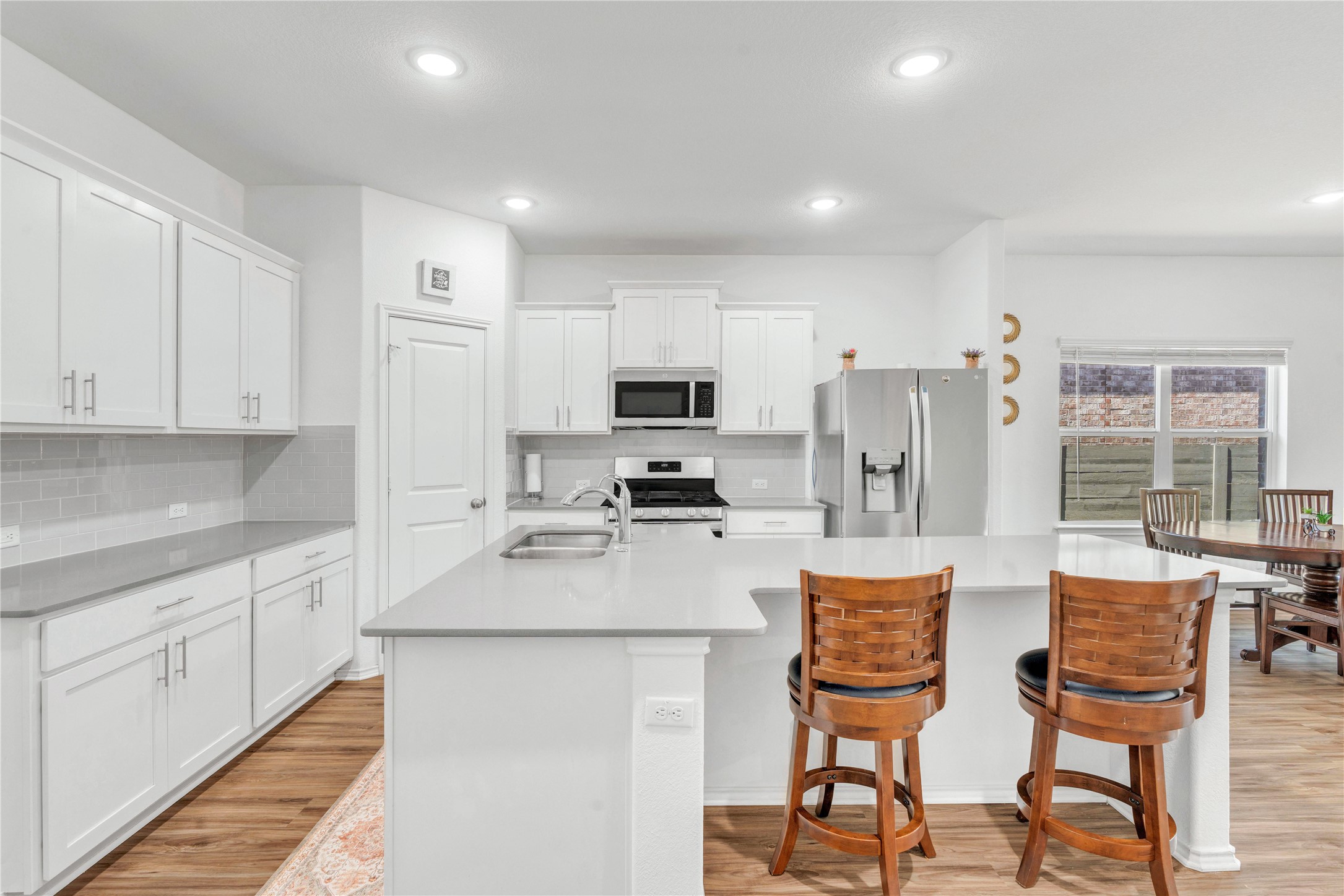 212 Saddle Mountain Road Georgetown, TX 78628 - Photo 9 of 38 a kitchen with stainless steel appliances granite countertop a stove a sink dishwasher a refrigerator and white cabinets with wooden floor
