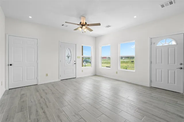 a view of an empty room with a window and wooden floor