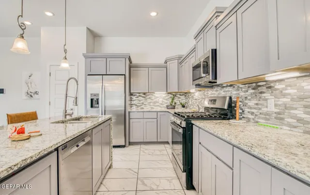 a kitchen with stainless steel appliances granite countertop a stove a sink and a microwave