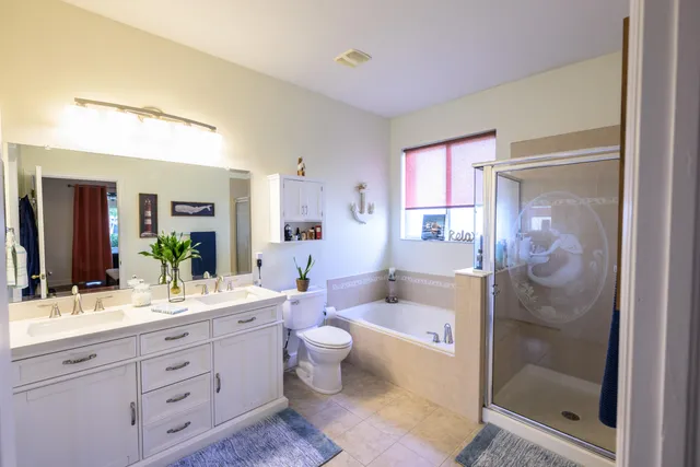 a spacious bathroom with a double vanity sink toilet mirror and shower