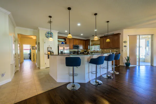 a kitchen with stainless steel appliances kitchen island granite countertop a stove top oven a sink with island and chairs