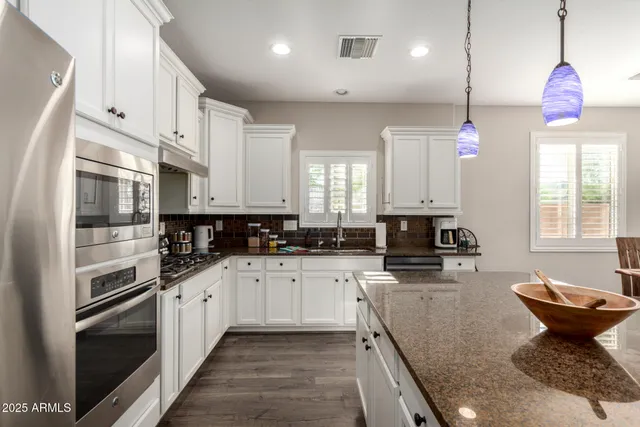 a kitchen with stainless steel appliances kitchen island granite countertop a sink a stove and cabinets