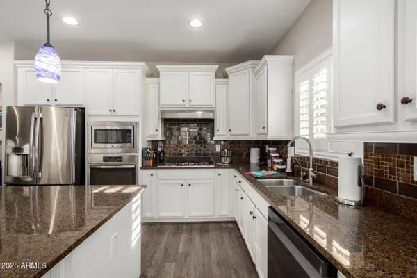 a kitchen with granite countertop a refrigerator a sink a stove and cabinets