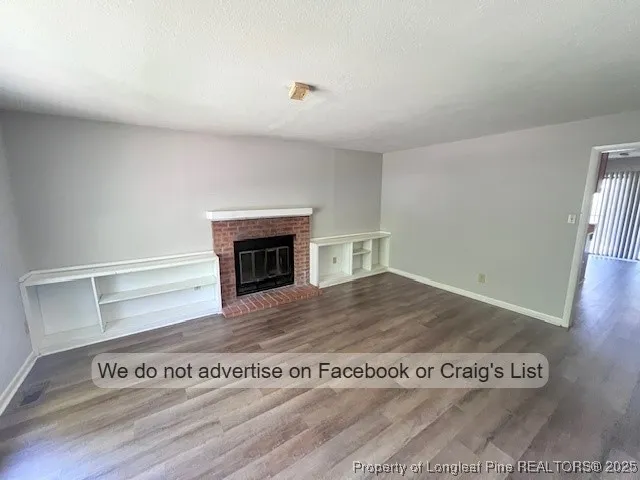 a view of kitchen and empty room with wooden floor