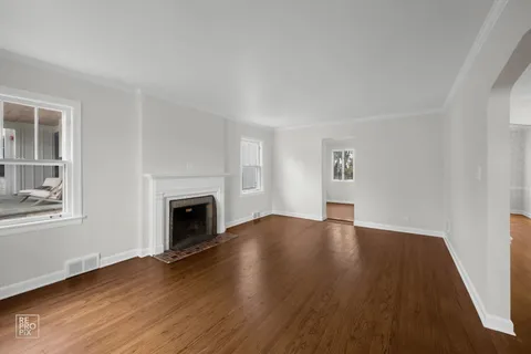 an empty room with wooden floor and a fireplace
