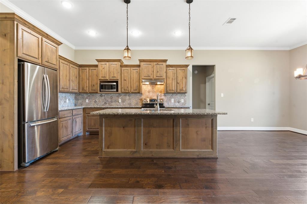 1617 Hawthorne Street Cleburne, TX 76033 - Photo 18 of 40 a kitchen with granite countertop a refrigerator a sink and wooden floor