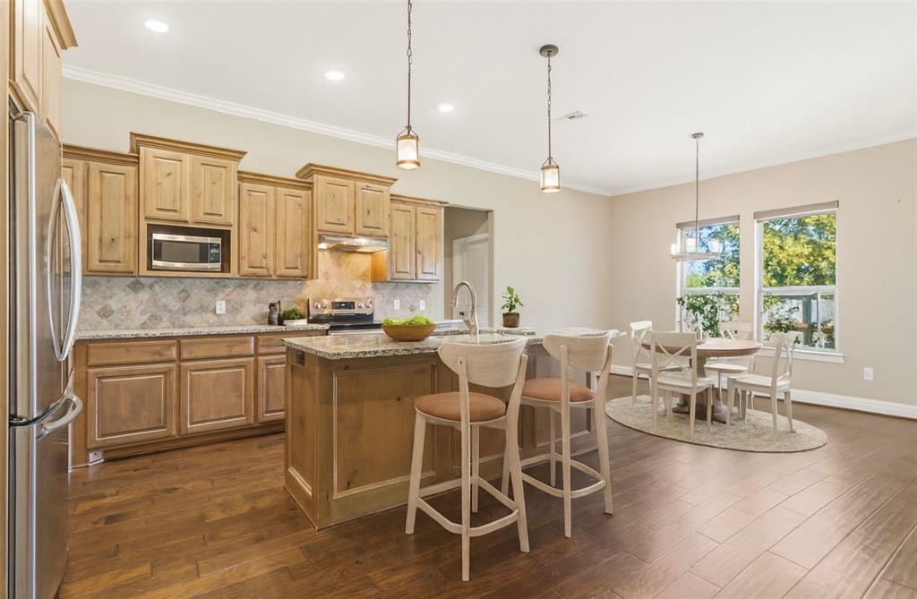 1617 Hawthorne Street Cleburne, TX 76033 - Photo 19 of 40 a kitchen with stainless steel appliances granite countertop a stove a sink dishwasher a dining table and chairs with wooden floor