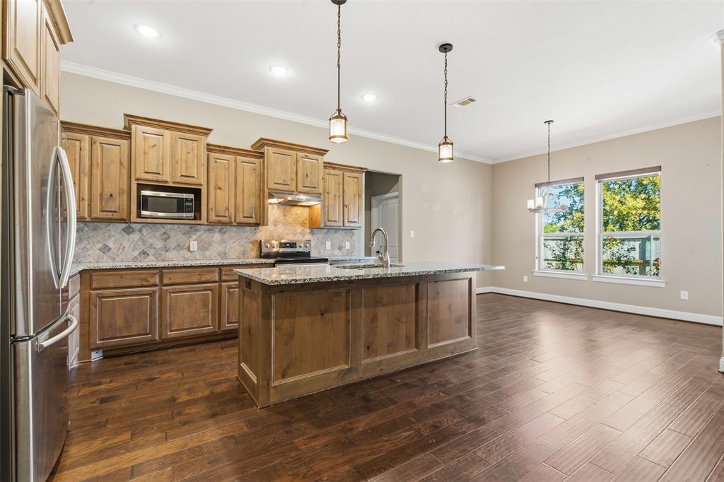 1617 Hawthorne Street Cleburne, TX 76033 - Photo 22 of 40 a large kitchen with granite countertop a stove a sink a center island a refrigerator and a wooden floor