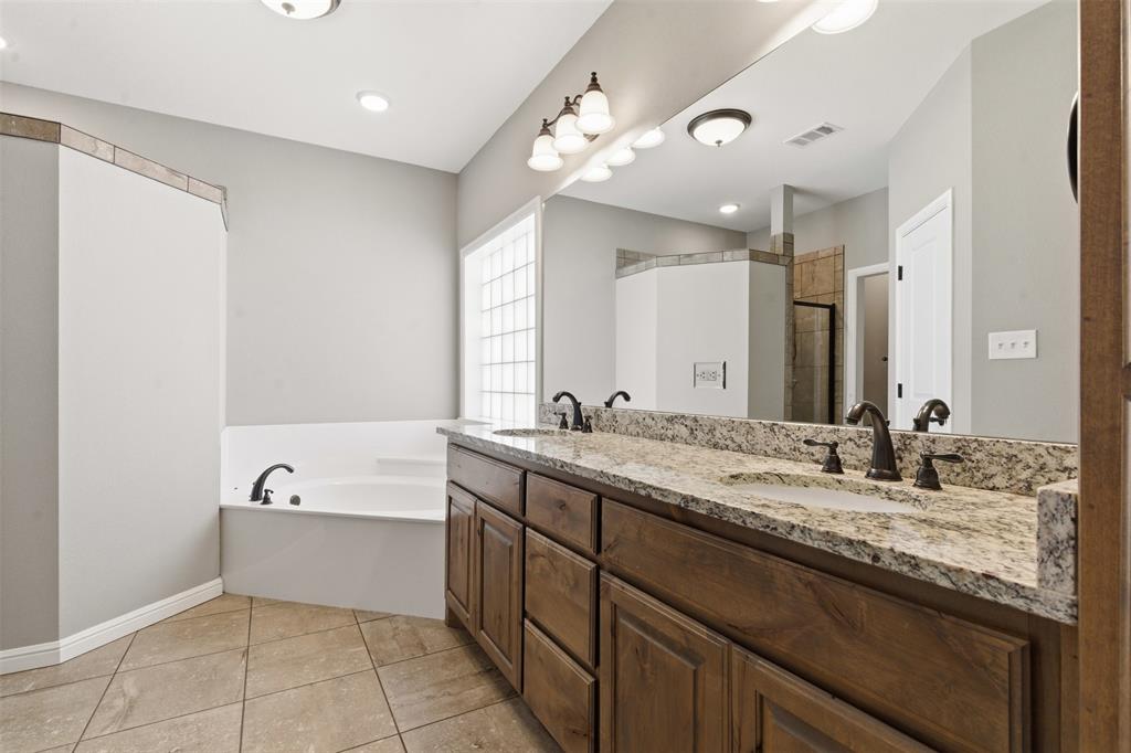 1617 Hawthorne Street Cleburne, TX 76033 - Photo 30 of 40 a bathroom with a granite countertop sink mirror and a bathtub