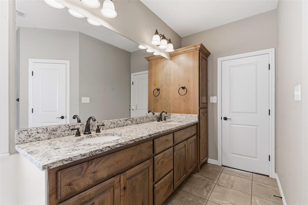 1617 Hawthorne Street Cleburne, TX 76033 - Photo 32 of 40 a bathroom with a granite countertop double vanity sink a mirror and a shower