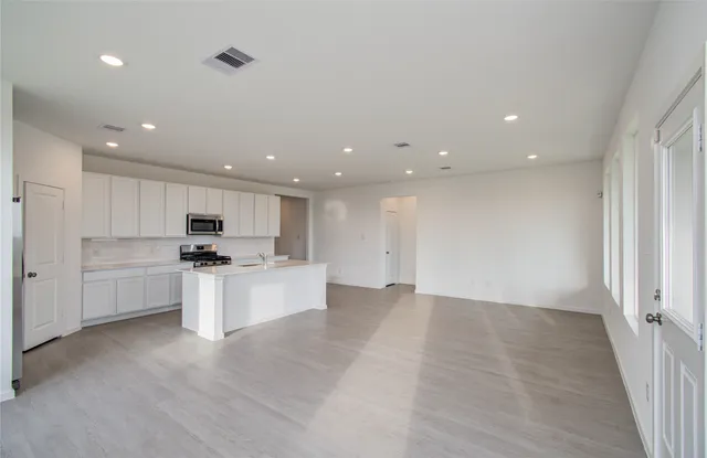 a view of kitchen with kitchen island a sink dishwasher a stove and a refrigerator with wooden floor