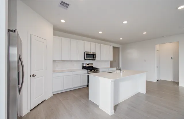 a kitchen with white cabinets and stainless steel appliances