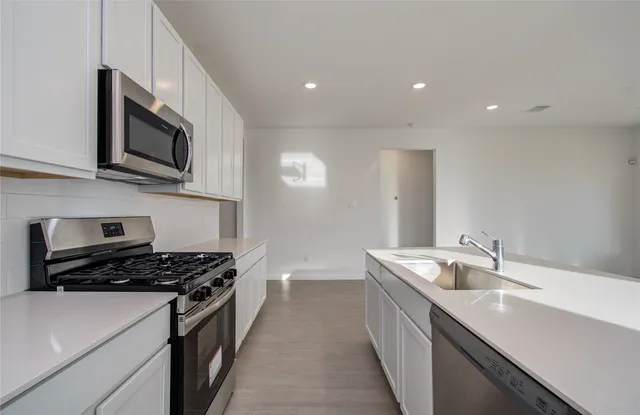 a kitchen with stainless steel appliances a sink a stove top oven a refrigerator a sink and dishwasher