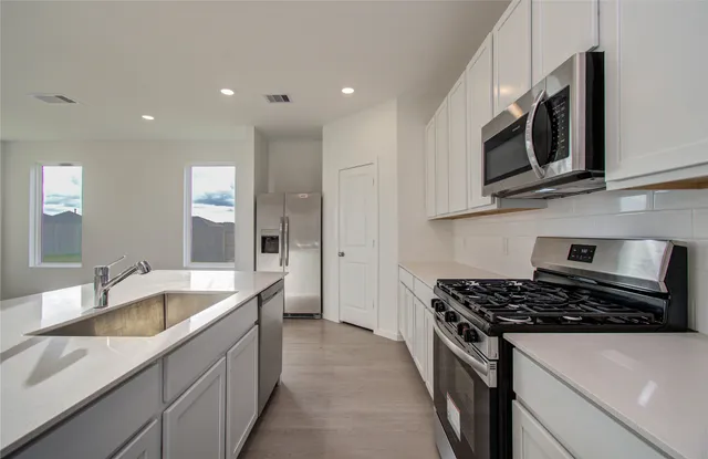 a kitchen with stainless steel appliances granite countertop a sink stove and microwave