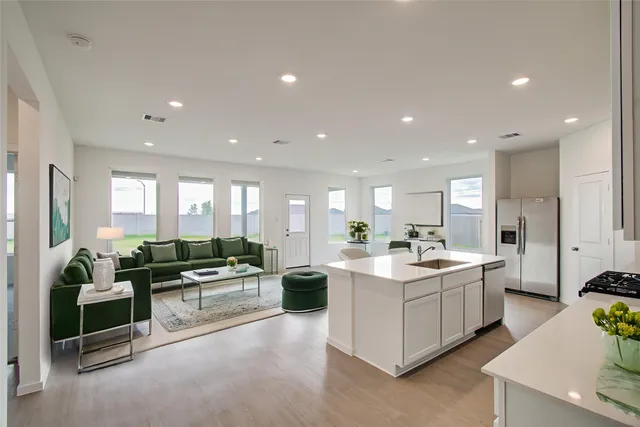 a living room with stainless steel appliances kitchen island granite countertop a sink and white cabinets