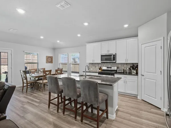 a kitchen with microwave a sink dishwasher a dining table and chairs with wooden floor