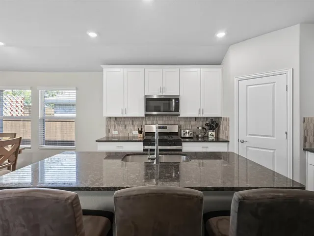 a kitchen with kitchen island granite countertop a sink and a stove top oven with wooden floor
