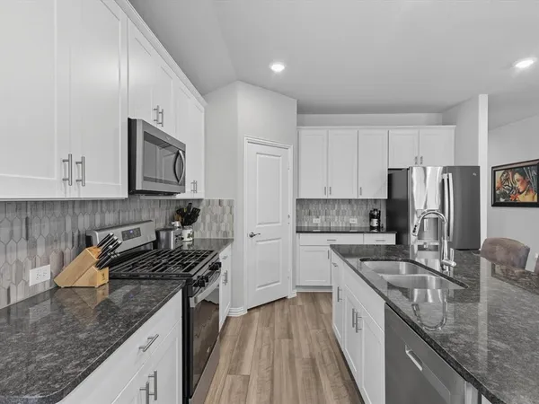 a kitchen with a sink stove top oven and refrigerator