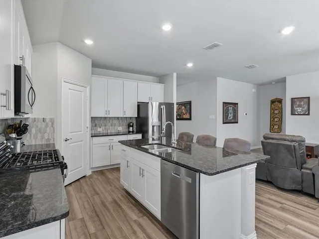 a kitchen with stainless steel appliances granite countertop a sink stove and refrigerator
