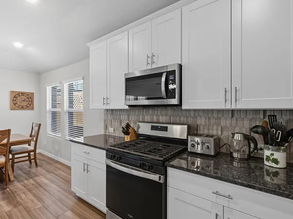 a kitchen with granite countertop white cabinets and black appliances