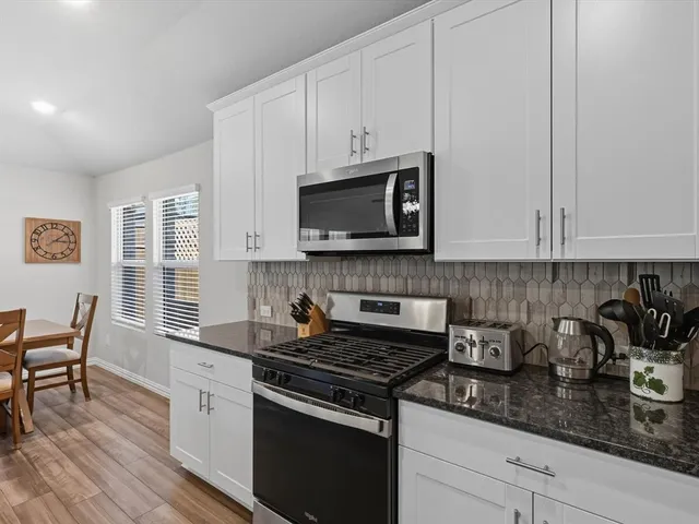 a kitchen with granite countertop white cabinets and black appliances