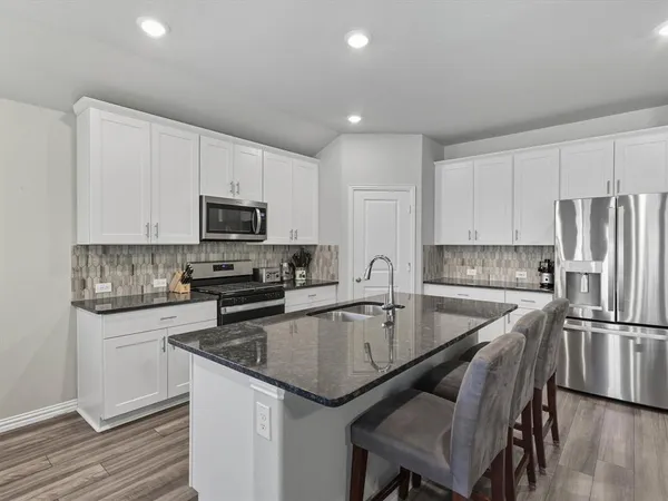 a kitchen with a center island white cabinets and stainless steel appliances