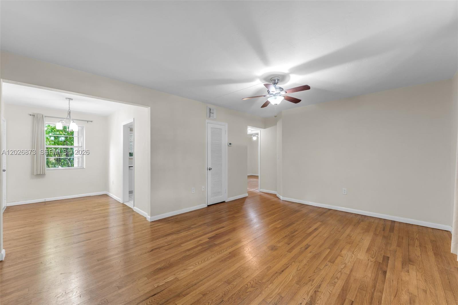 5590 Southwest 78th Street, Unit 133B Miami, FL 33143 - Photo 1 of 18 an empty room with wooden floor chandelier fan and windows