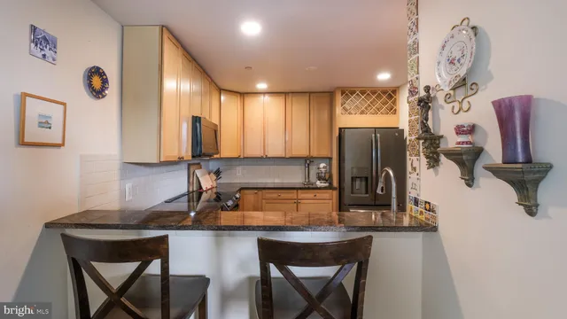 a kitchen with stainless steel appliances granite countertop a sink refrigerator and cabinets
