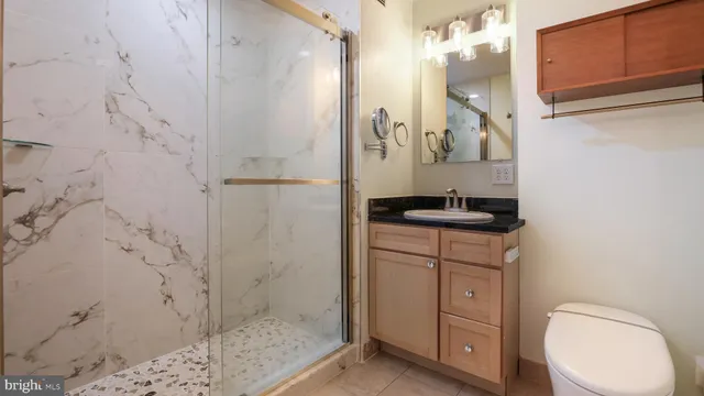 a bathroom with a granite countertop sink a toilet and shower