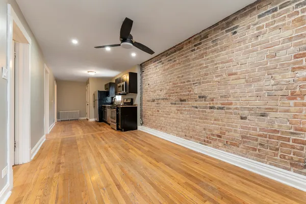 a view of empty room with kitchen and wooden floor