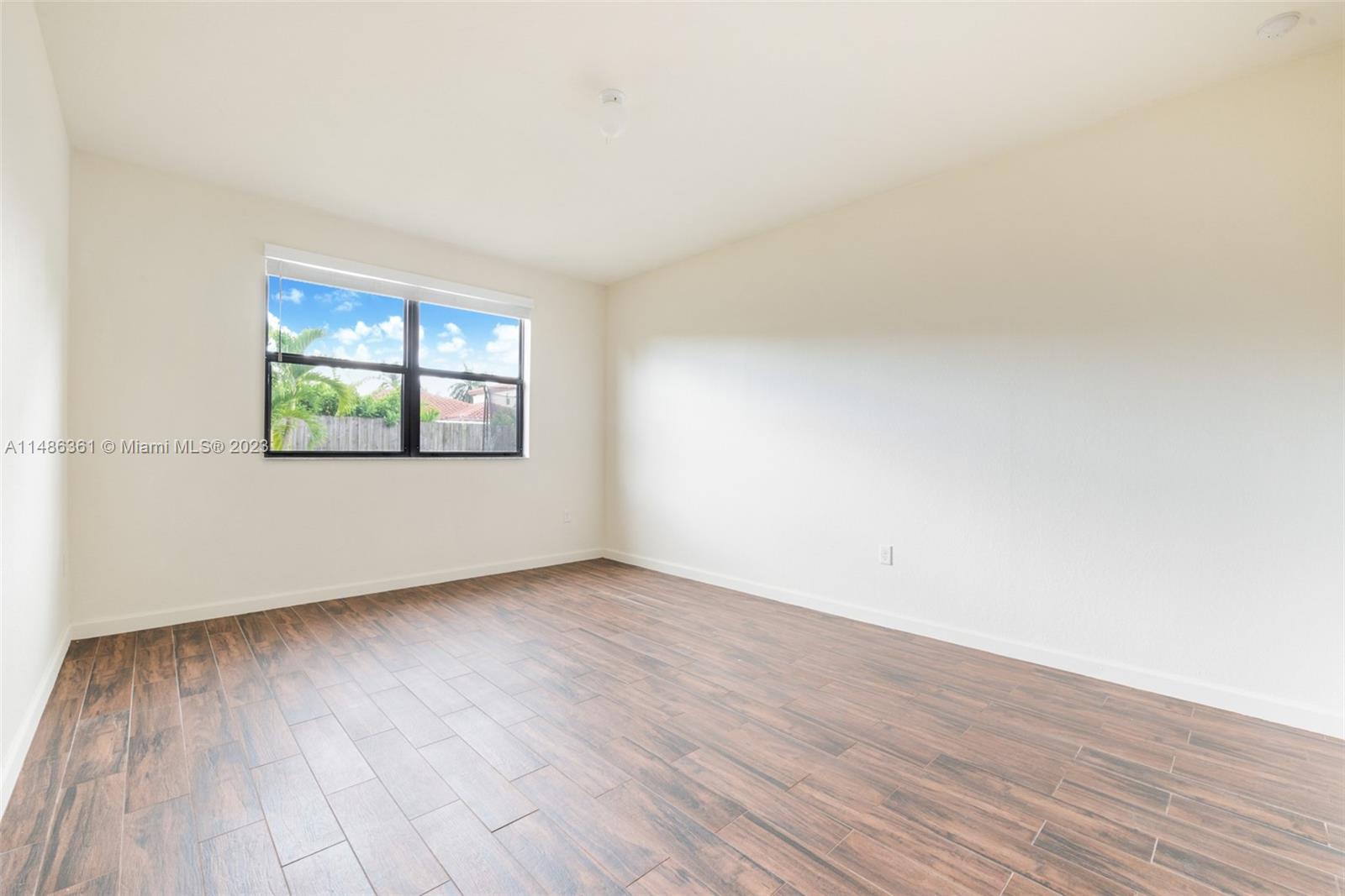 15218 Southwest 173rd Lane Miami, FL 33187 - Photo 10 of 14 an empty room with wooden floor and windows