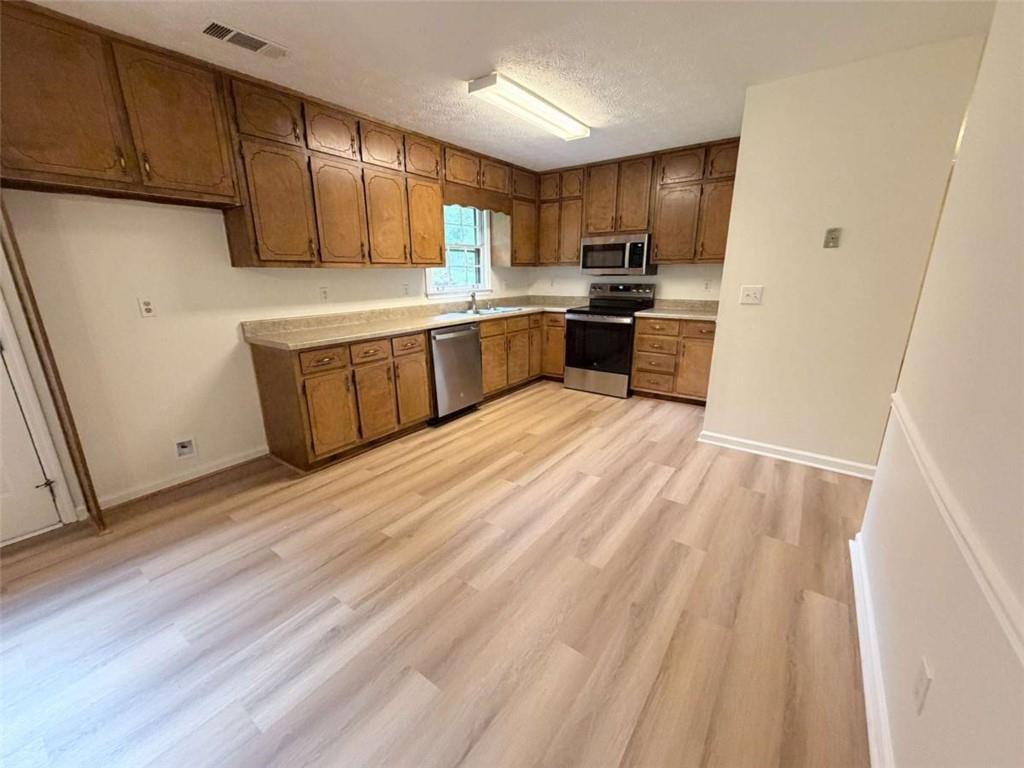 185 Roberts Road Covington, GA 30016 - Photo 12 of 25 a kitchen with wooden floors stainless steel appliances a sink and cabinets