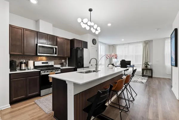 a kitchen with stainless steel appliances a stove refrigerator sink dining table and chairs