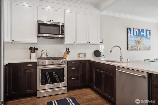 a kitchen with stainless steel appliances granite countertop a sink and dishwasher a stove top oven with wooden floor