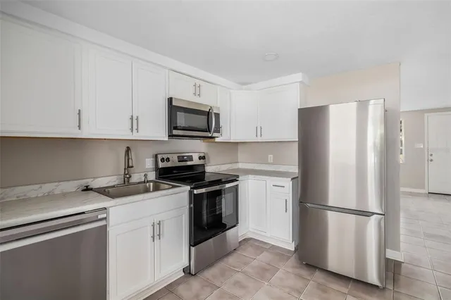 a kitchen with stainless steel appliances granite countertop a refrigerator stove a sink and dishwasher with white cabinets