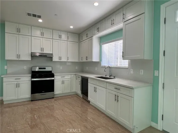 a kitchen with granite countertop white cabinets white appliances and sink