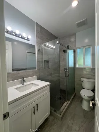 a bathroom with a shower sink mirror and toilet