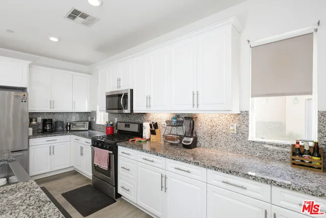 a kitchen with granite countertop a sink a stove and cabinets