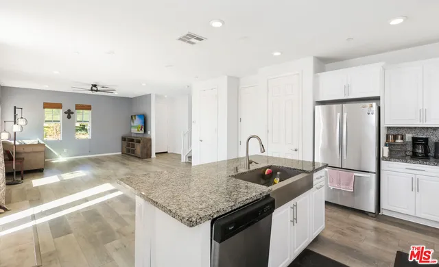 a kitchen with stainless steel appliances granite countertop a sink refrigerator and cabinets