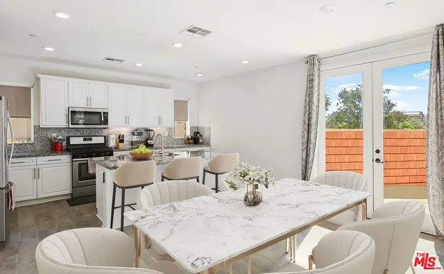 a dining room with stainless steel appliances kitchen island granite countertop a dining table chairs and a microwave