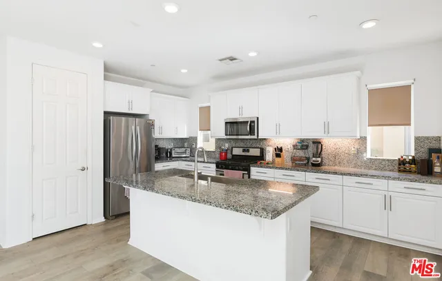 a kitchen with stainless steel appliances granite countertop a refrigerator a sink a stove a microwave and cabinets