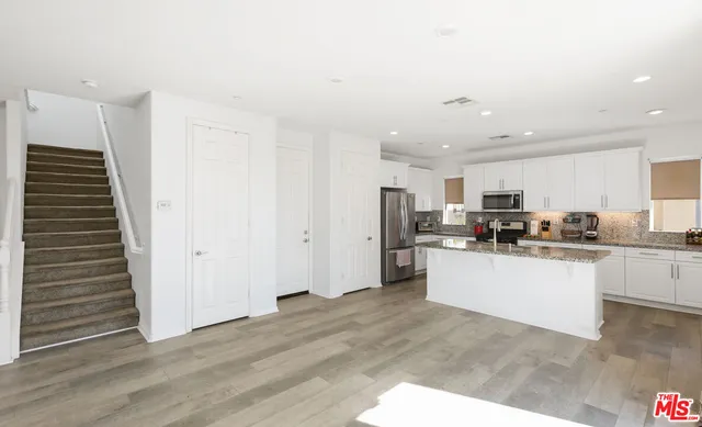 a kitchen with stainless steel appliances a refrigerator and white cabinets