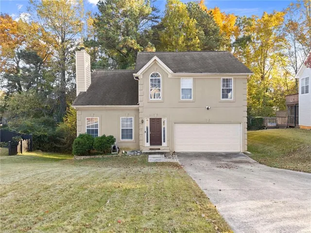 a view of a house with a yard and large tree