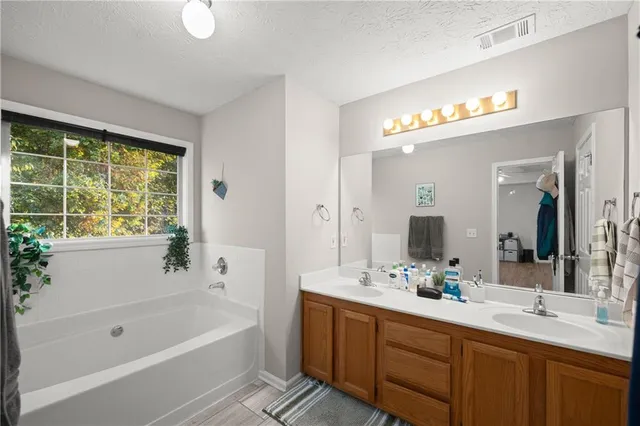 a bathroom with a tub a sink and a large mirror