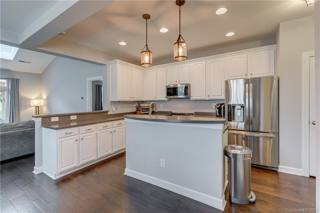 6743 Dusty Saddle Road Charlotte, NC 28277 - Photo 9 of 47 a kitchen with kitchen island granite countertop a refrigerator a stove a sink and white cabinets with wooden floor